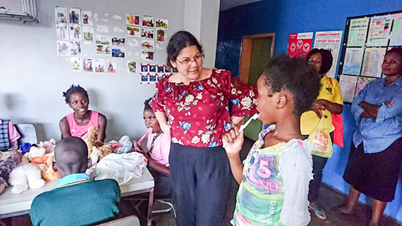 Betsy instruerar en lite pojke i tandborstning på ett barnhem, där de delade ut tandborstar till barnen och pratade munhygien.