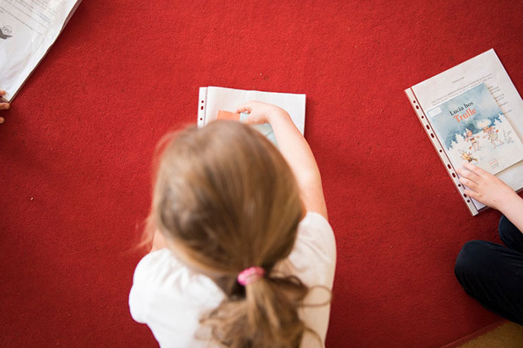 Flicka pysslar på golvet.