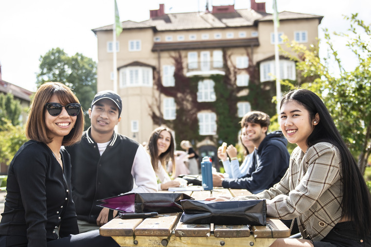 Studenter sitter utomhus på högskolans campus.