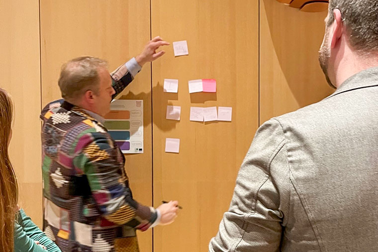 Konferensdeltagare s&auml;tter upp Post-it-lappar.