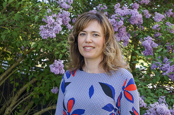 Biträdande professor Daniela Argento framför syrenbuskar.