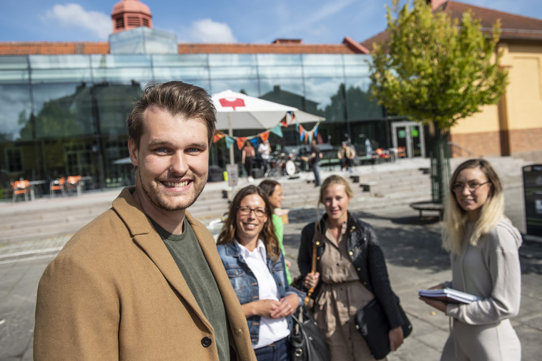 Tre personer utomhus på campus.