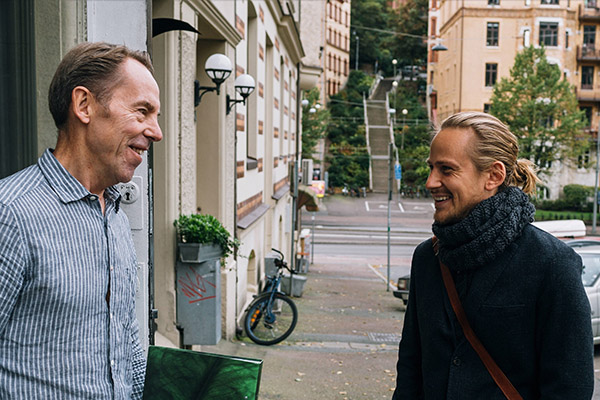 Äldre herre och ung kille vid husentré.