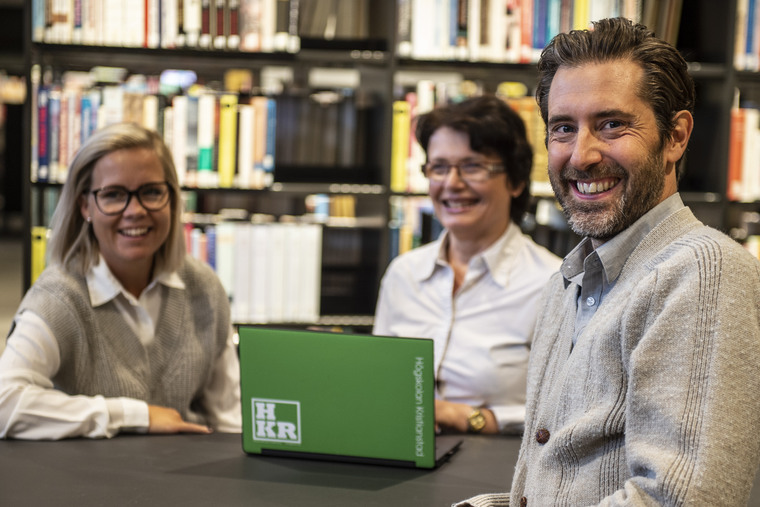 Tre personer pratar vid en dator.