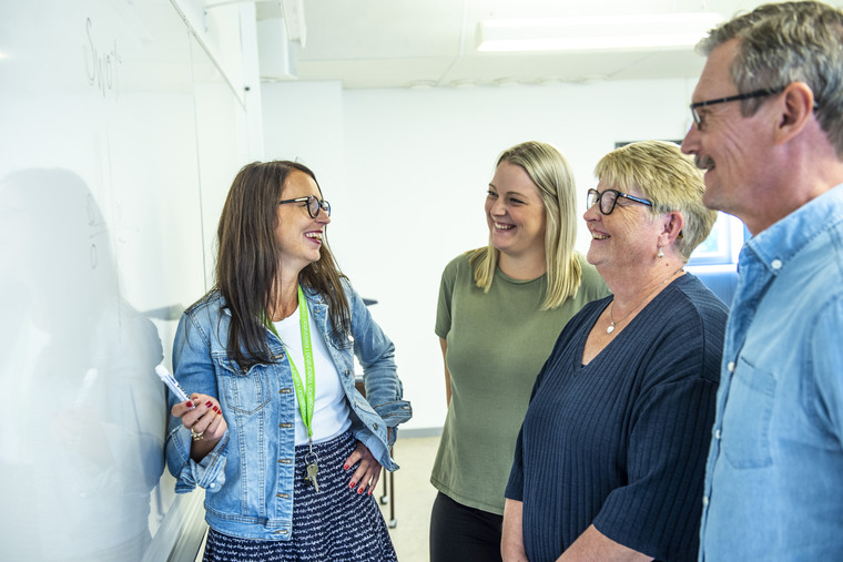 Fyra personer samtalar vid en whiteboard.