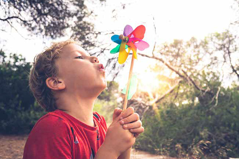 Pojke blåser på vindsnurra.