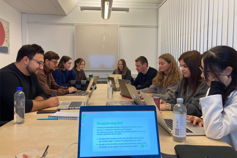 Studenter sitter runt ett konferensbord.