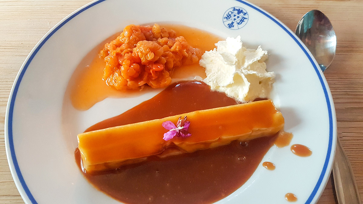 I fj&auml;llstationens restaurang f&aring;r vi smaka p&aring; Laponia. H&auml;r en efterr&auml;tt p&aring; kaffeost med hjortron, vispgr&auml;dde och kola, med en liten rosa blomma fr&aring;n mj&ouml;lk&ouml;rt, eller rallarros som den ocks&aring; kallas. Foto: Johanna Gr&ouml;nroos