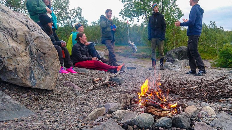 Landskapsvetarstudenten Alexander Lundgren valde att h&aring;lla sin presentation nere p&aring; Langas strand. Medvetet gav han publiken den f&auml;ngslande utsikten i fonden medan han f&ouml;rklarade ekosystemtj&auml;nsterna i omr&aring;det och elden sprakade. Foto: Fabian Rimfors