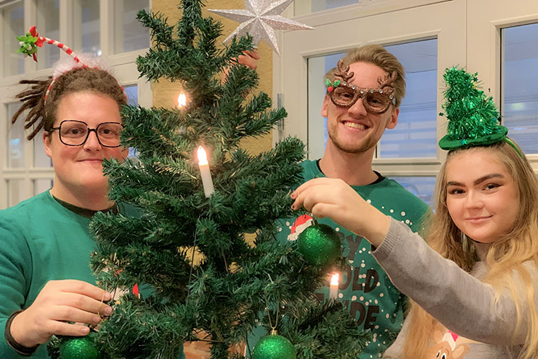 Tre studenter vid en julgran.