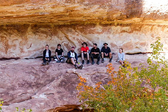 Studenter sitter under en av &rdquo;broarna&rdquo; av sandsten i Natural Bridges National Monument i Utah.