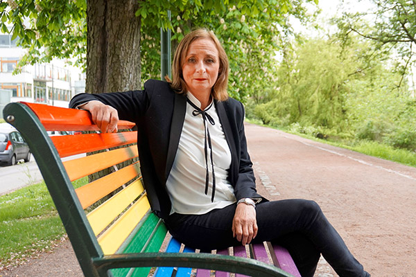 Eva Sch&ouml;mer p&aring; en regnb&aring;gsf&auml;rgad parkb&auml;nk.