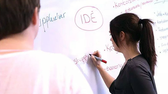 student skriver idé på whiteboard.