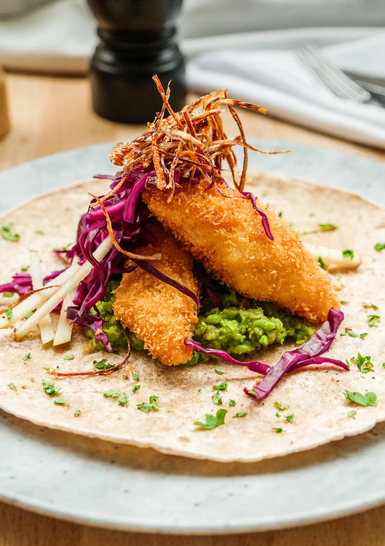Taco med pankofriterad braxen, &auml;rtguacamole, syrad r&ouml;dk&aring;l, &auml;pple och friterad schalottenl&ouml;k.