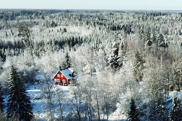Agnes röda stuga i ett vinterlandskap i skogen.