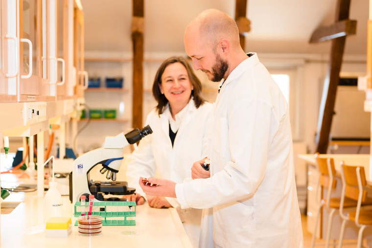 Adam och Viktoria vid ett mikroskop.