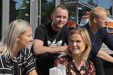 Ungdomar på trappa i solen.