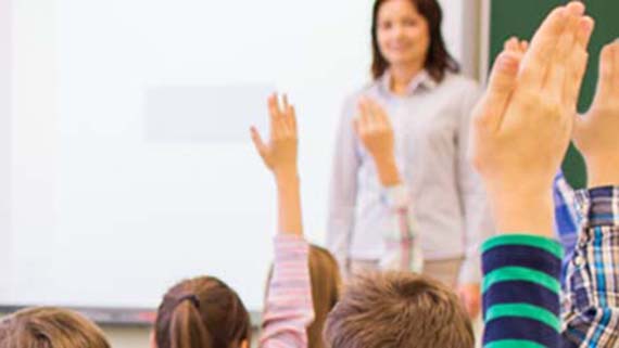 Barn r&auml;cker upp handen i klassrum.