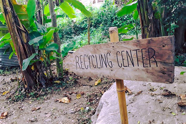 Skylt till &aring;tervinning och bananplantor.