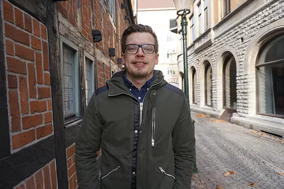 André står på en gata och tittar in i kameran
