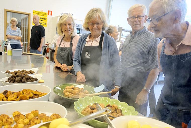 Fyra personer vid sk&aring;lar och fat med mat.
