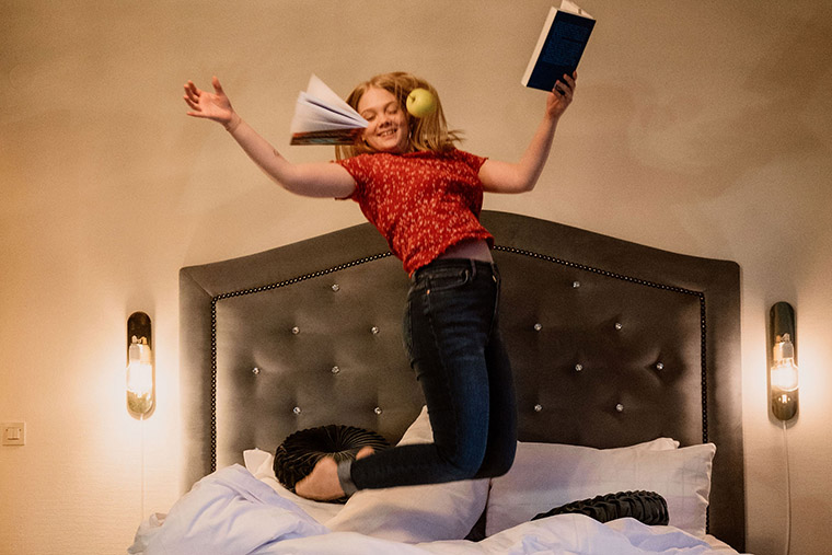 Tjej hoppar i hotellsäng.