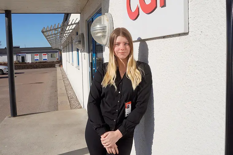 Lizette står i solen utanför sin arbetsplats och tittar in i kameran