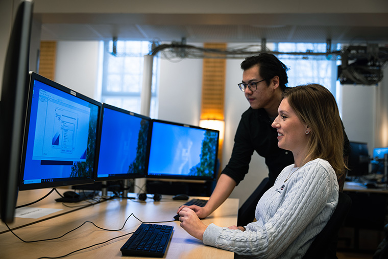 Studenter arbetar tillsammans vid datorskärmar