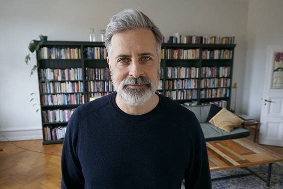 David tittar in i kameran, bakom finns bokhyllor