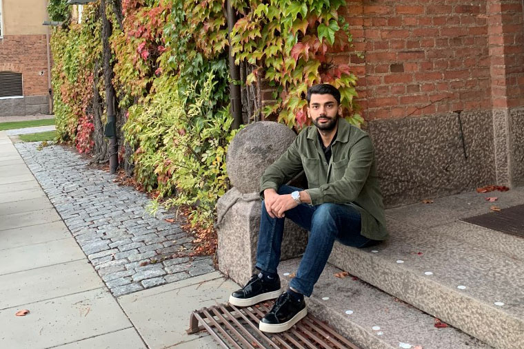 Mohammad sitter på en trappa på campus