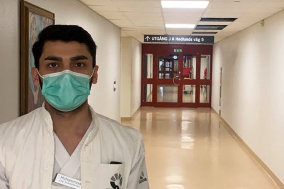 Mohammad Mustafa står i en sjukhuskorridor med vita kläder och munskydd
