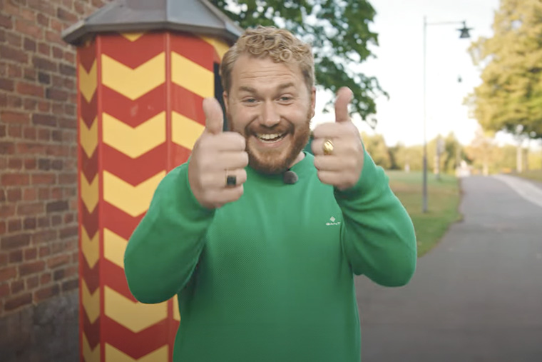 Leende kille ikl&auml;dd gr&ouml;n tr&ouml;ja  g&ouml;r tummen upp.