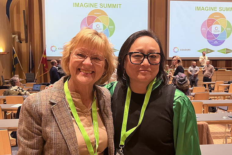 Två personer framför skärm med texten Imagine Summit.