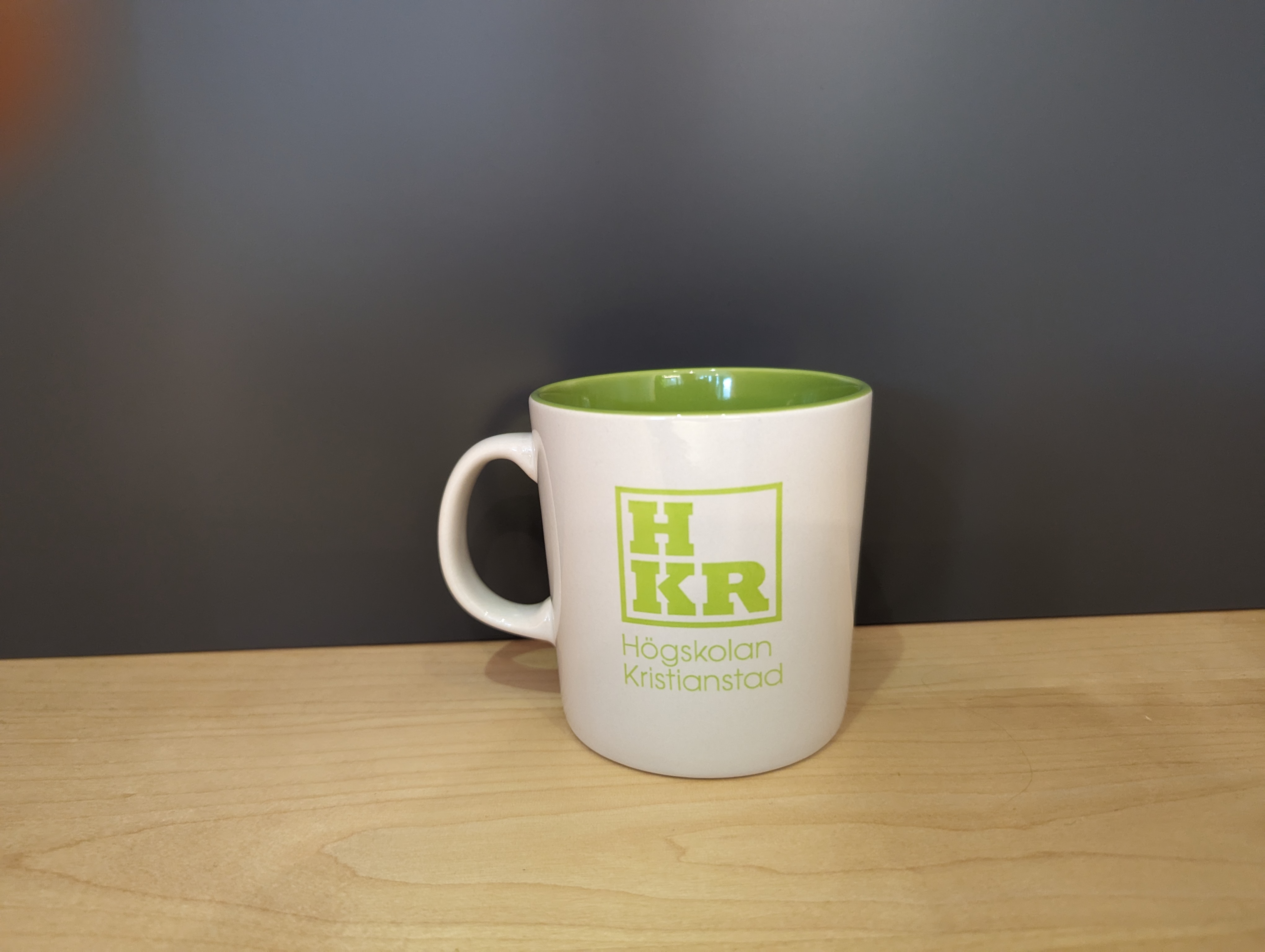 Vit kaffemugg med grön insida och grön HKR logga