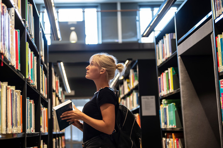 Student tittar på böcker i biblioteket.