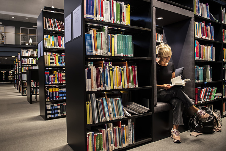 Student i biblioteket som bläddrar i bok.