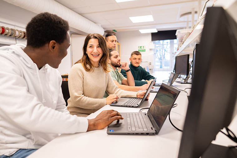 Studenter och lärare vid datorer.