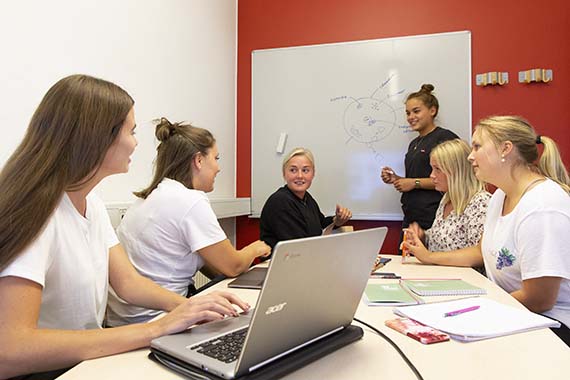 Studenter som arbetar i grupp framför whiteboard