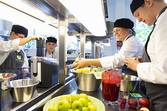 Studenter i gastronomiköket, med gröna och röda äpplen